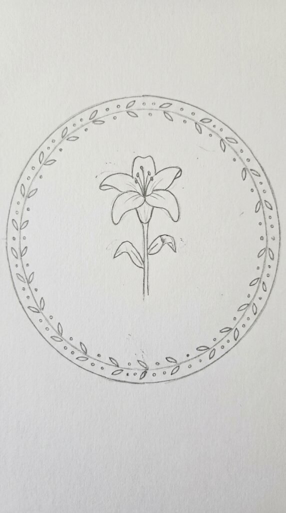 Lily drawing inside a circle frame with decorative border, pencil outline on white paper.